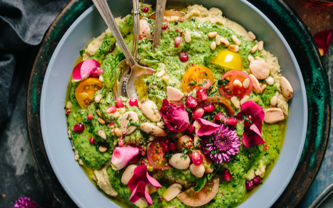 A bowl of guacamole with an assortment of other ingredients sprinkled on top